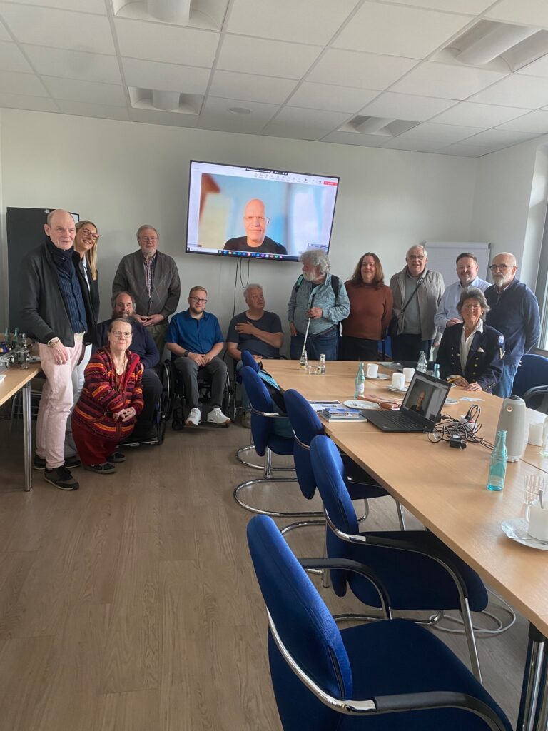 Das Foto zeigt 13 der nach Ende der Versammlung noch anwesenden Teilnehmenden der Gründungssitzung der LAG Selbsthilfe Niedersachsen am 7. Mai 2025 in Hannover. Auf dem Bildschirm ist Holger Borner zu sehen, Rechtsanwalt aus Bonn, der die Gründung mit juristischem Rat im Auftrag der BAG Selbsthilfe begleitet hat.