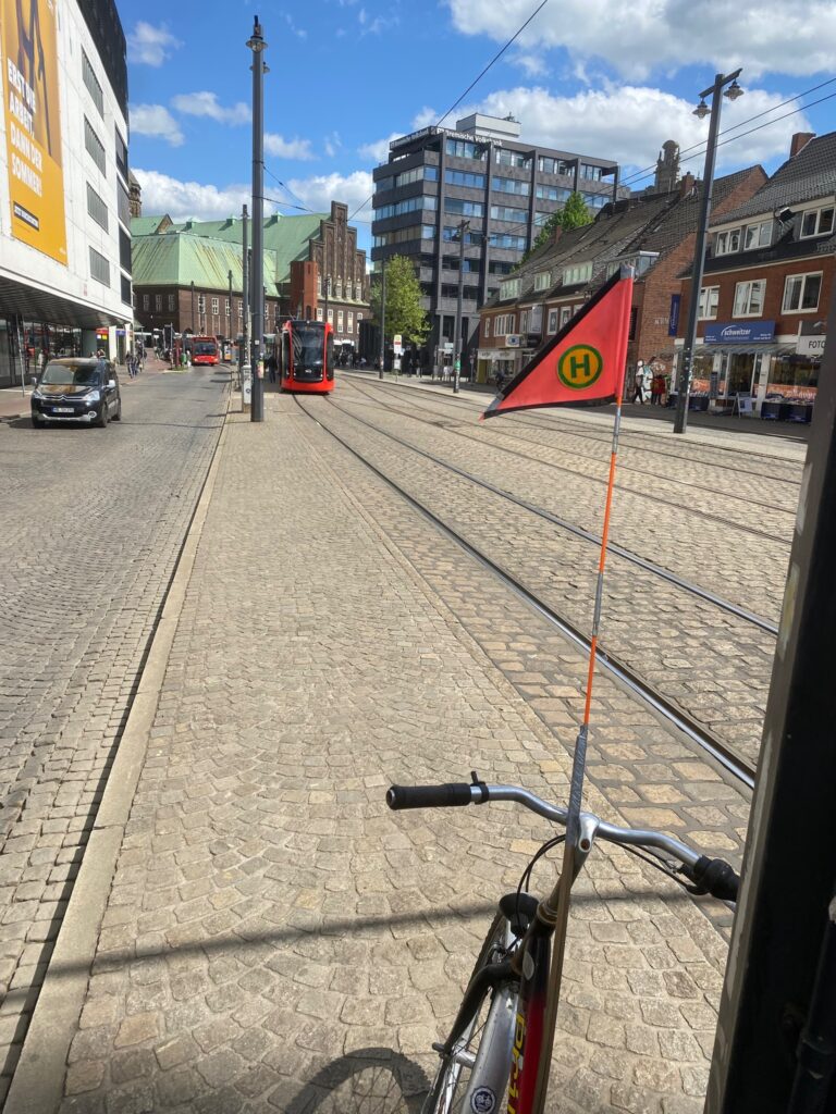 Fast schon an der Martinistraße steht ein Fahrrad mit einem Fähnchen mit Haltestellensymbol für eine Straßenbahn. Dort wäre künftig die Haltestelle der Straßenbahnlinien 4, 6 und 8 und aller Busse, die linke und rechte Weserseite verbinden. Damit würde der Weg viel zu weit beim Umsteigen auf die Linien 2 und 3.