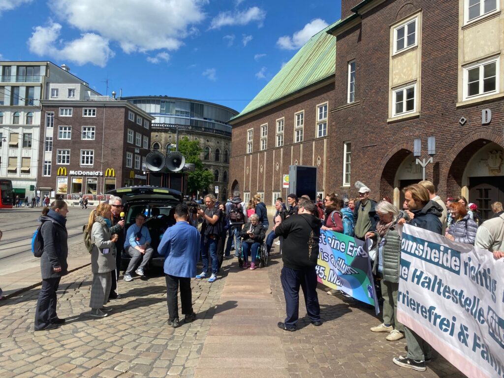 Dr. Joachim Steinbrück spricht zu den rund 300 Demonstrant:innen vor der Glocke. Unsere Forderung: Die Haltestellen dürfen nicht weitere 200 Meter auseinandergelegt werden!