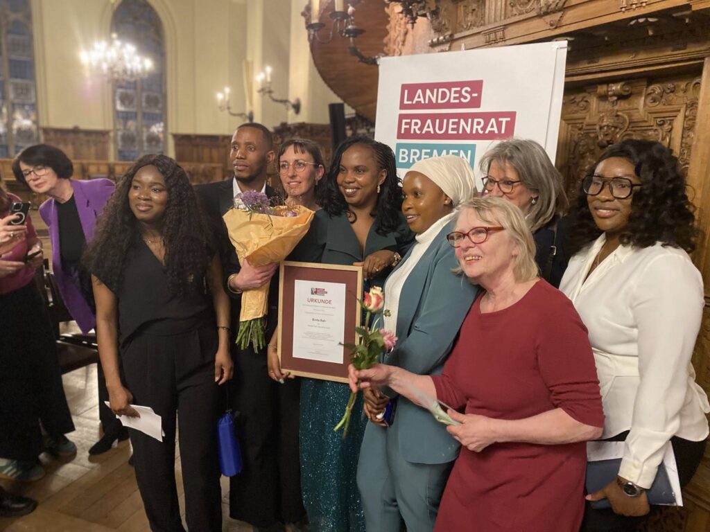 Binta Bah mit ihrer Auszeichnung und im Kreise der Mitglieder von Lundu e.V.