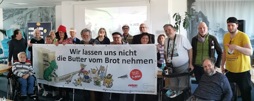 Das Team des AK Bremer Protest mit rund 20 Leuten am Protestbanner "Wir lassen uns nicht die Butter vom Brot nehmen"., mit unseren Trollen, die dem Anti-Inklusionsdrachen das Geld für mehr Teilhabe wieder abnehmen wollen.