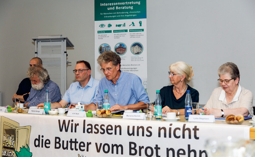 Auf dem Foto sind die LAGS-Vorstandsmitglieder zu sehen, von links nach rechts: Christian Malnati, Jürgen Karbe (1. Vorsitzender), Patrick George, H.-P. Keck, Marianne Korinth und Lydia Stegmann. Vor dem VOrstandstisch hängt das Motto-Banner des 5. Mai 2026 "Wir lassen uns nicht die Butter vom Brot nehmen!"